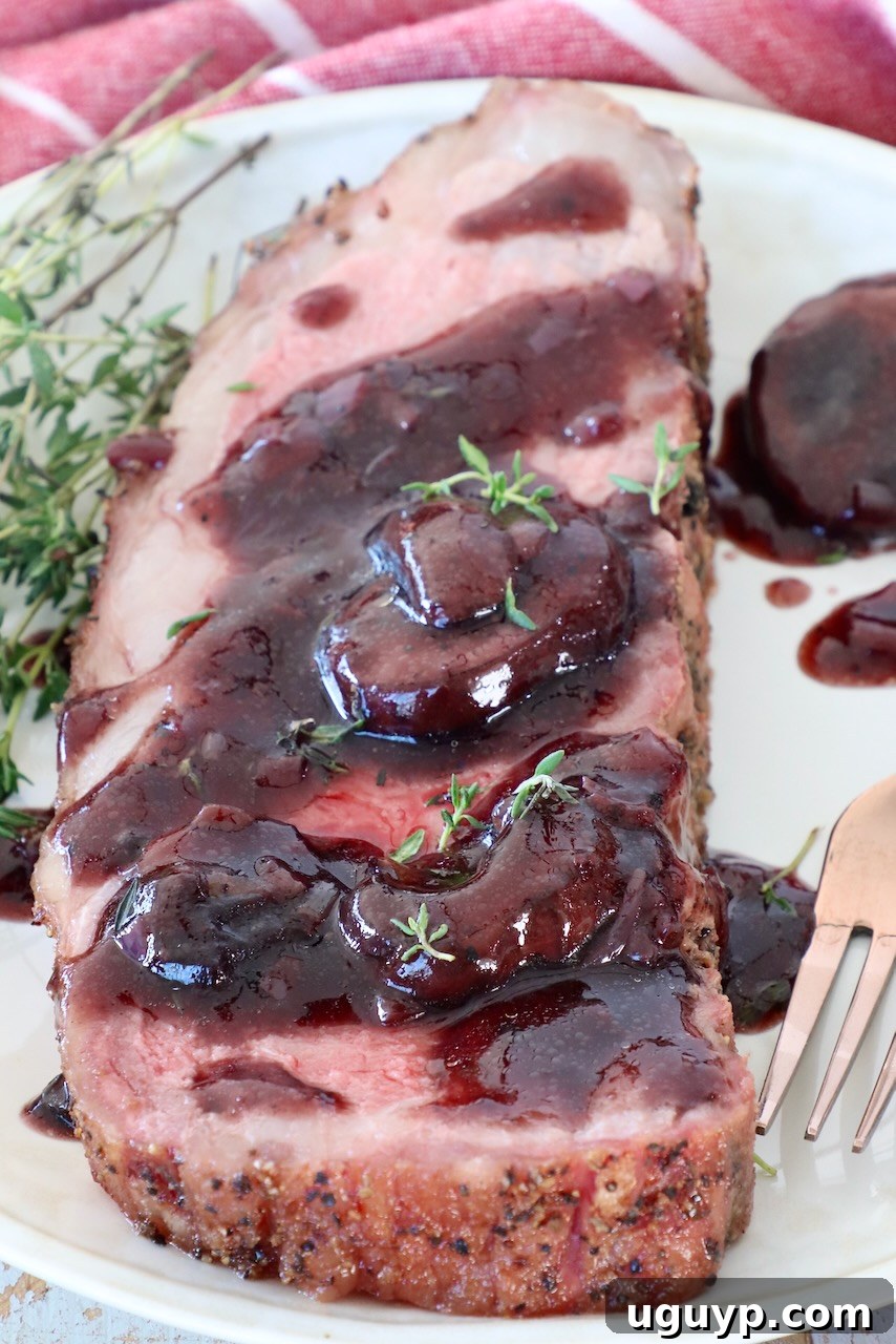 A slice of smoked New York Strip Steak on a plate, generously covered in red wine sauce.