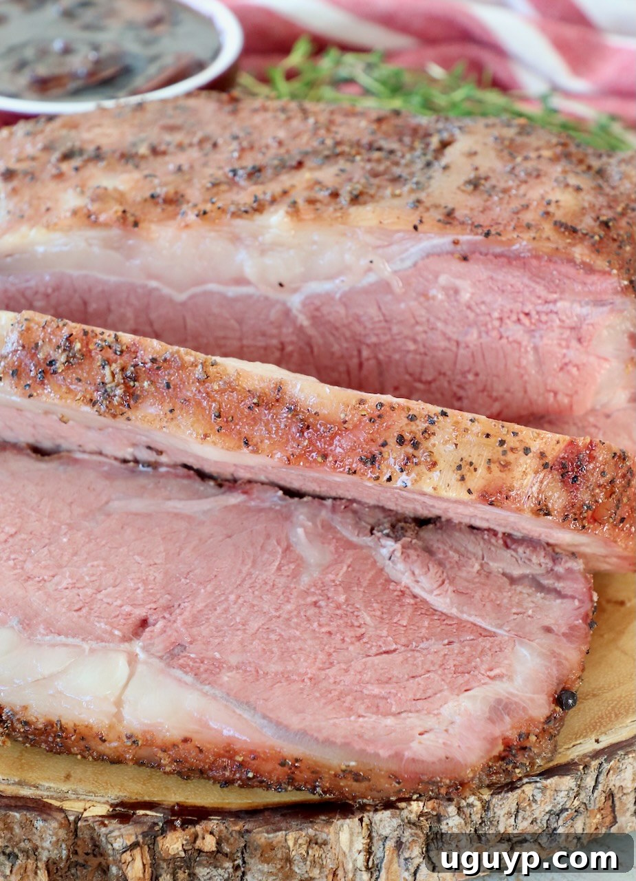 Perfectly sliced, smoked New York Strip Roast arranged on a wooden board for serving.