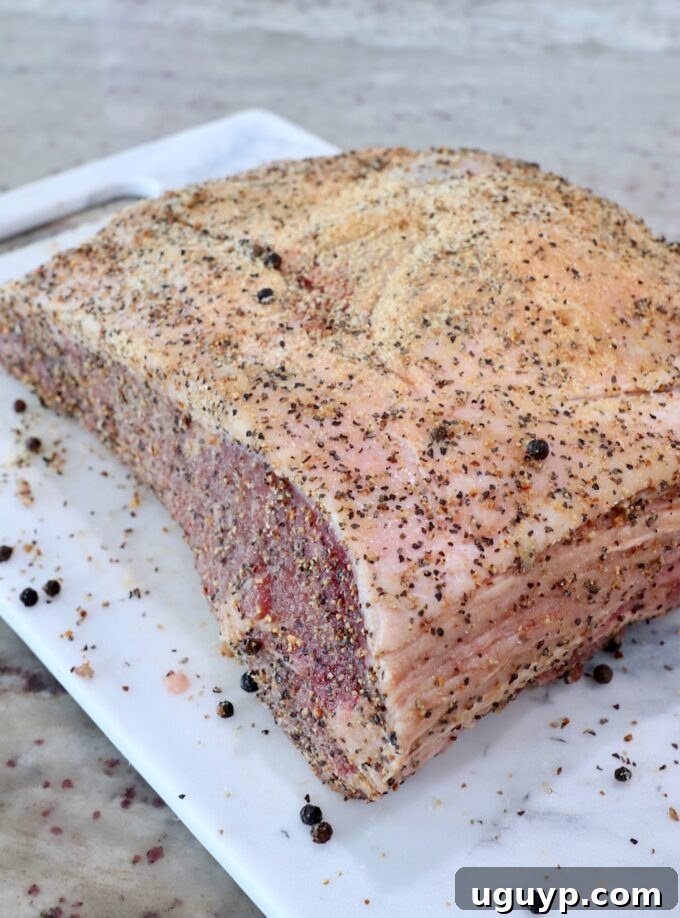 Seasoned strip roast on a cutting board, ready for the smoker.