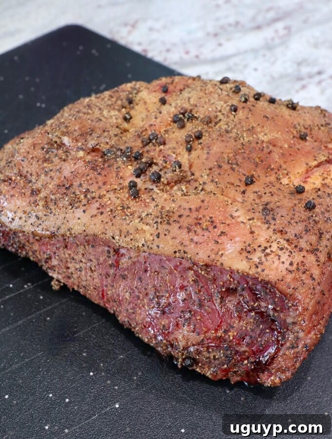 Smoked New York Strip Roast resting on a cutting board, covered with foil.