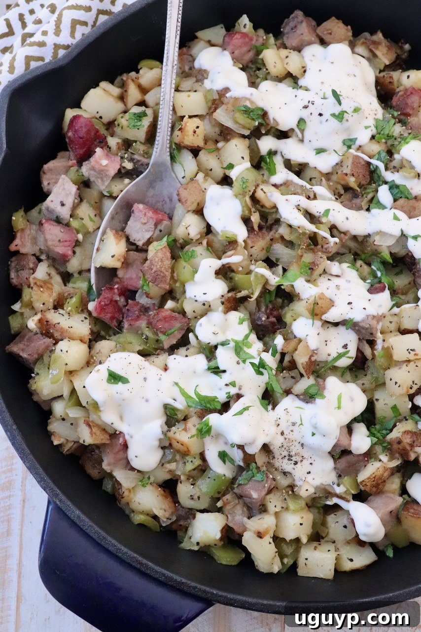 Diced steak and potato hash sizzling in a skillet, generously topped with a creamy provolone cheese sauce.