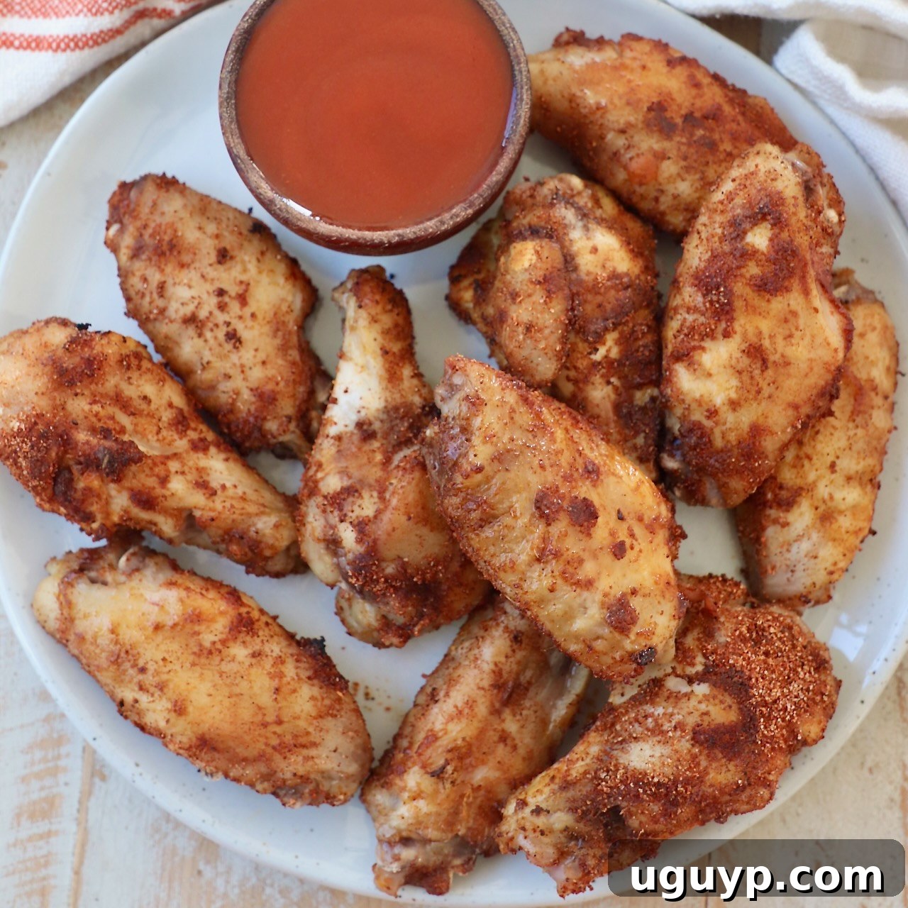 cooked chicken wings on plate with small bowl of buffalo sauce