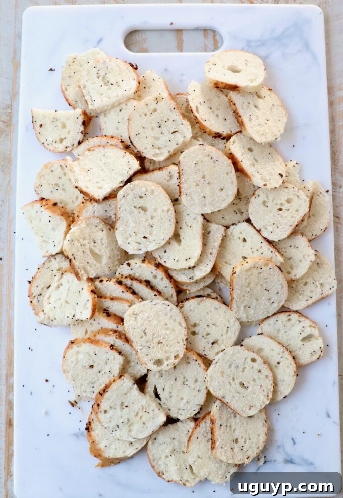 Bagels sliced into thin chips on a cutting board, ready for seasoning.