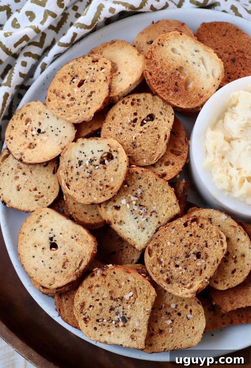 Close-up of everything bagel chips on a plate, with a small ceramic bowl of cheddar cheese spread in the background.