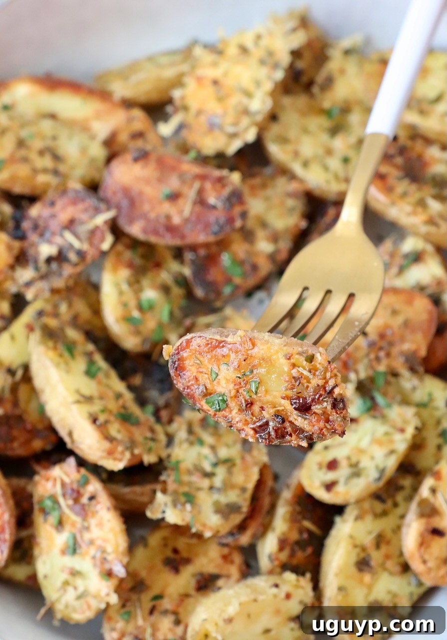 A serving of roasted mini potatoes with a fork, highlighting their crispy texture and delicious seasoning.