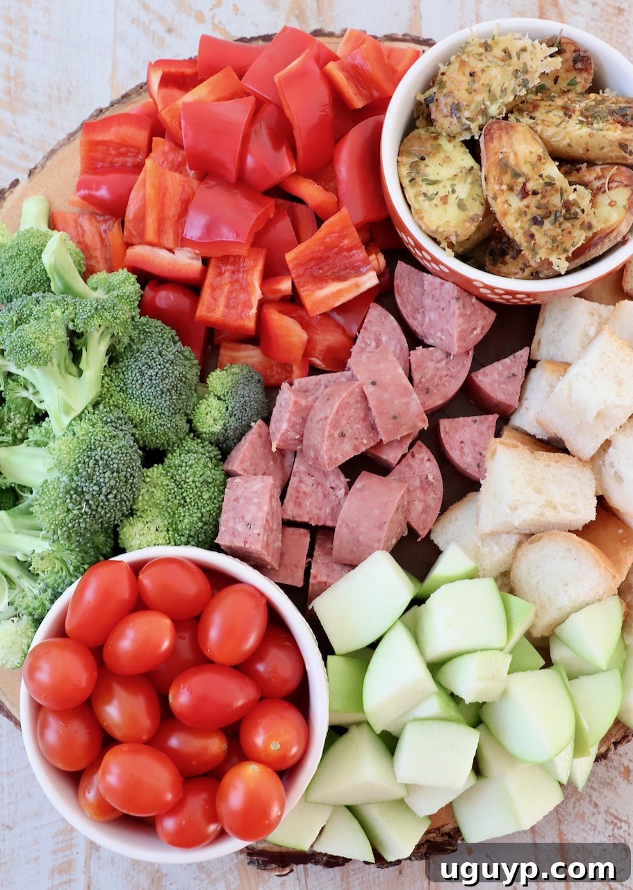 diced vegetables, apples, beef stick and cubes of bread on a wood tray