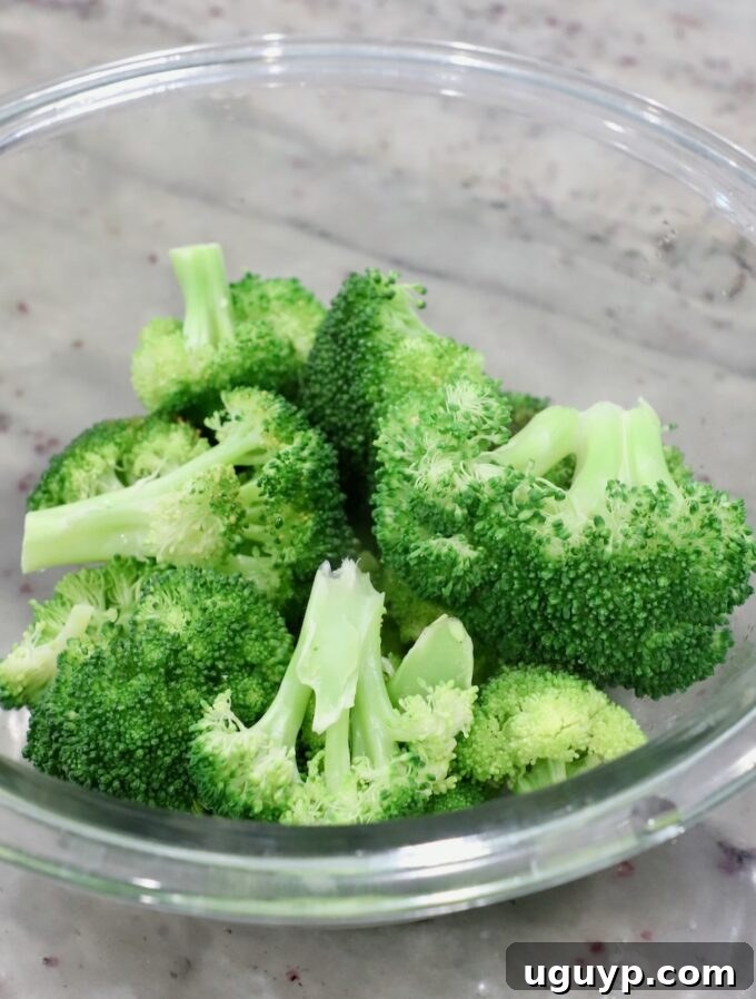 Perfectly steamed broccoli florets in a glass serving bowl.