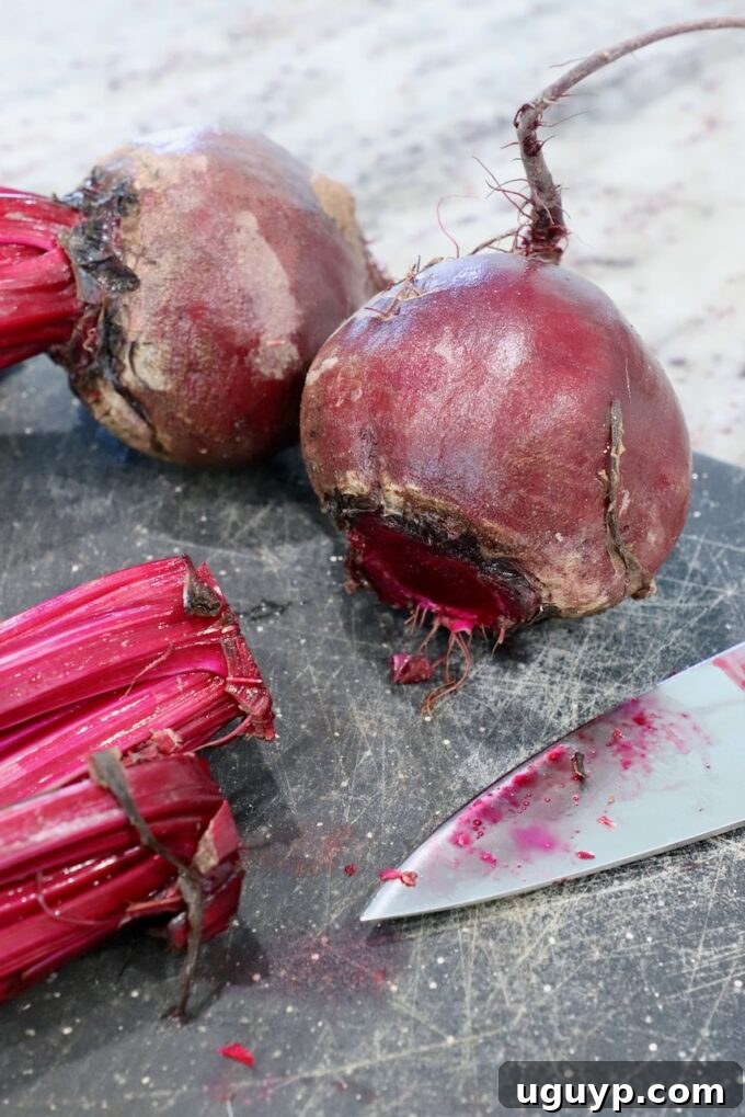 raw beets on cutting board with the stems cut off