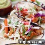 Grilled shrimp tacos in corn tortillas topped with slaw and cotija cheese