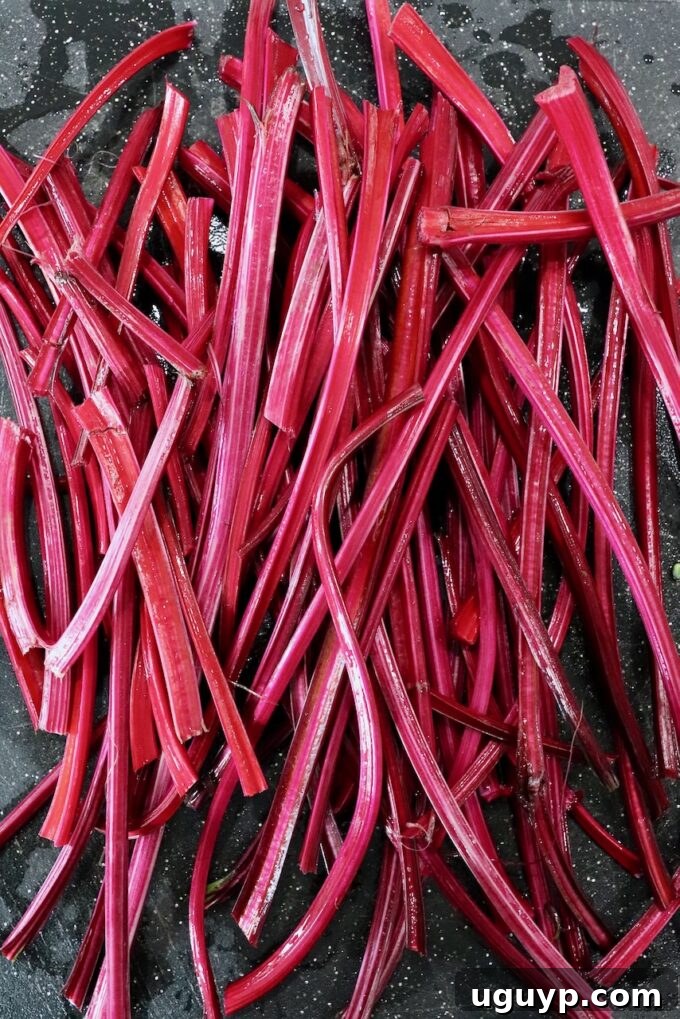 Beet stems freshly cut and arranged on a wooden cutting board, showcasing their vibrant color.