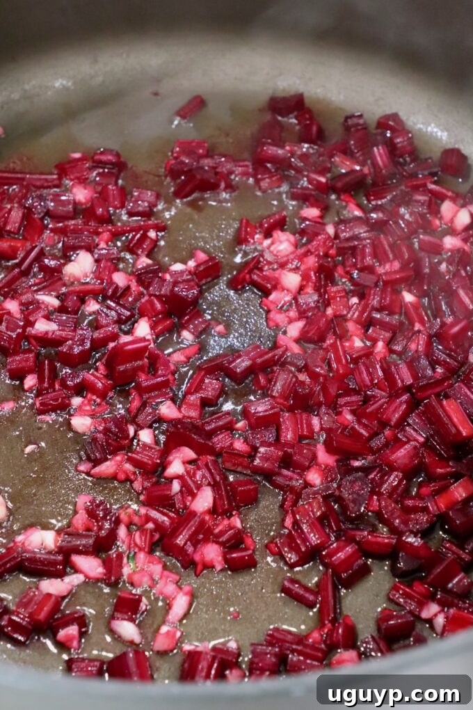 Minced beet stems and garlic simmering in a large pot, releasing aromatic flavors.