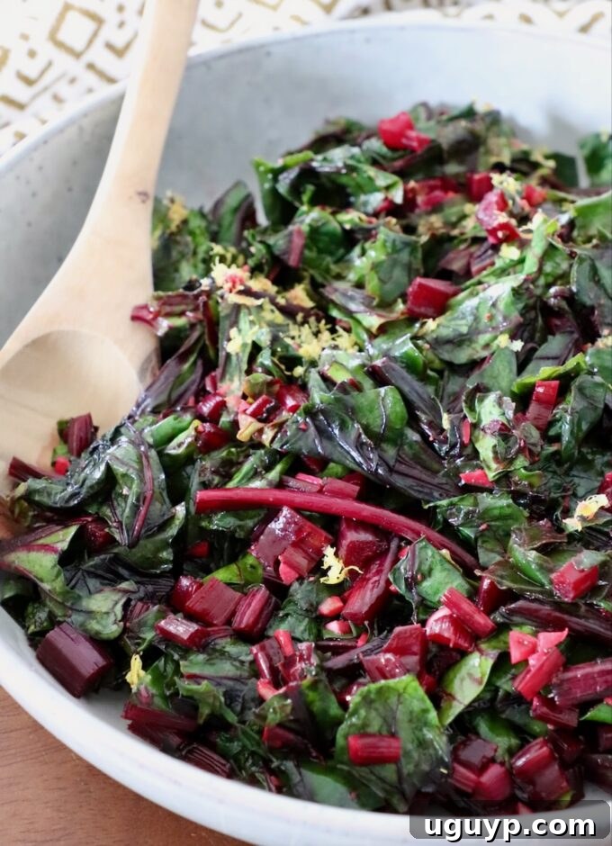 A serving of sautéed beet greens in a rustic bowl, garnished with a wooden spoon.