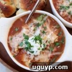 lasagna soup, topped with cheese, in bowl with spoon