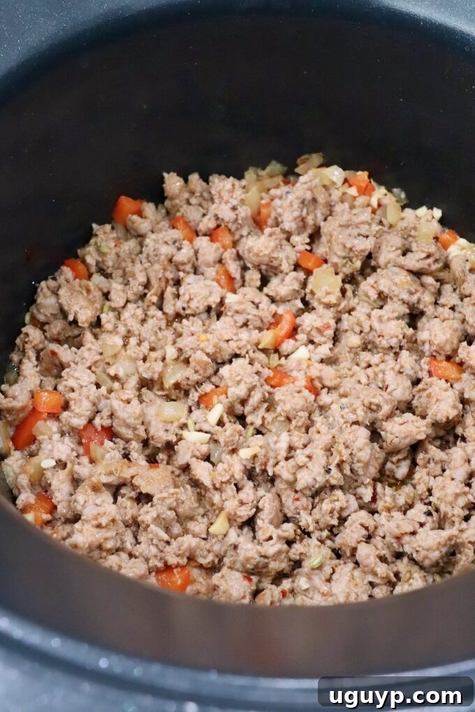 Cooked Italian sausage and diced vegetables in a pot after browning.