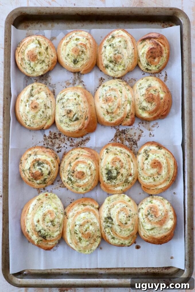 Freshly baked creamy pickle crescent rolls on a parchment-lined baking sheet, golden brown and ready to serve.