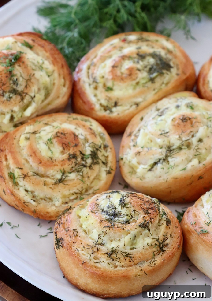 Baked pickle crescent rolls presented elegantly on a white plate, garnished with fresh dill, ready to be enjoyed.