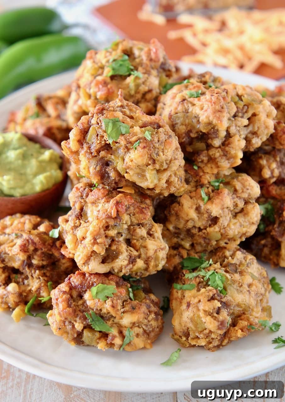 Sausage balls on a plate with creamy avocado sauce in a small bowl, garnished with fresh herbs.