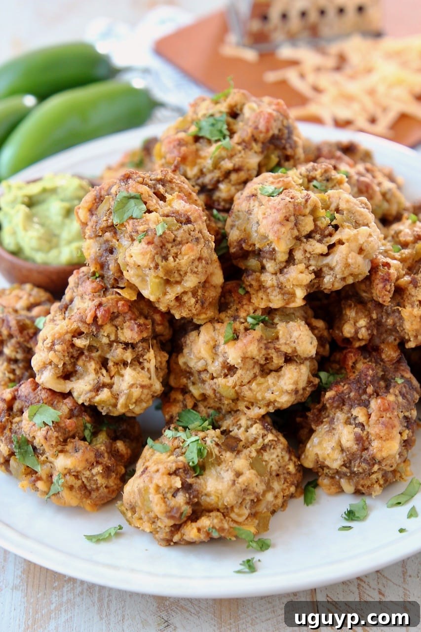 Mexican Chorizo Bisquick Sausage Balls on plate with creamy avocado sauce in small bowl, jalapenos and shredded cheddar cheese