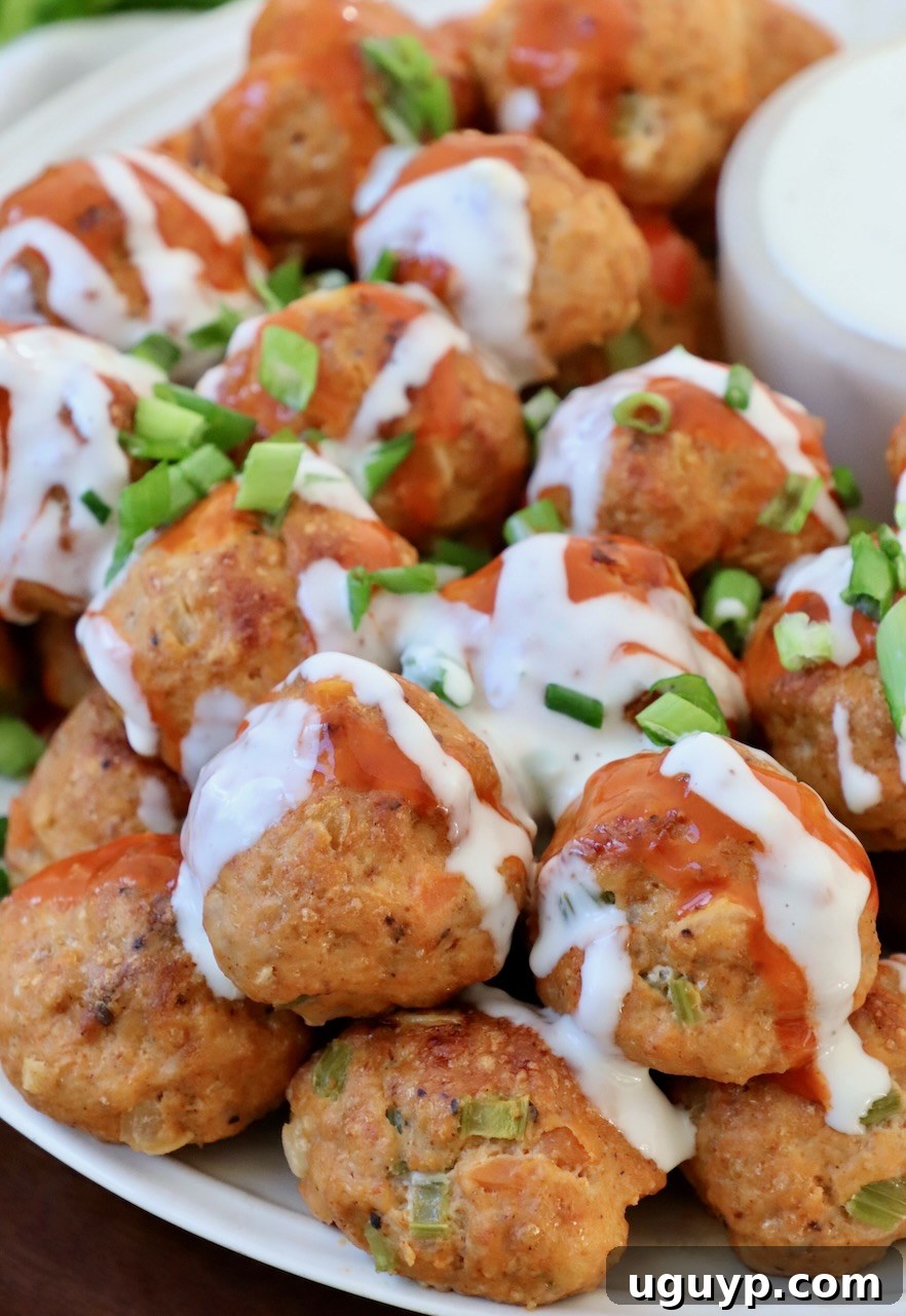 Stacked buffalo chicken meatballs generously drizzled with creamy blue cheese dressing and tangy buffalo sauce, ready to be enjoyed as a delicious appetizer or main course.