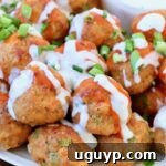 Buffalo chicken meatballs arranged on a plate, featuring a delicious drizzle of buffalo sauce and a side of creamy blue cheese dressing.