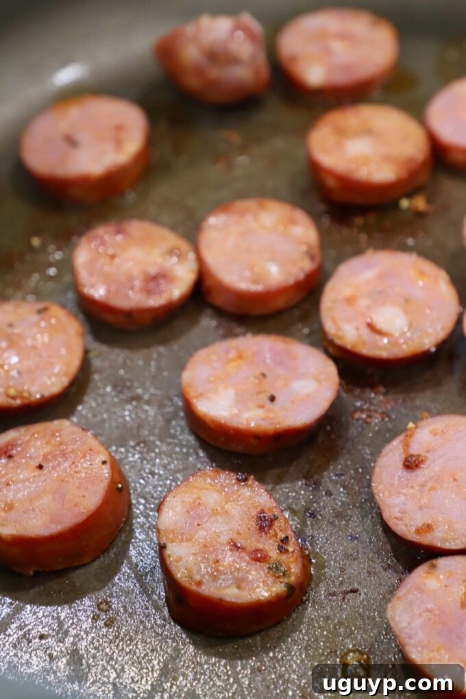 Sliced Andouille sausage cooking in a pan