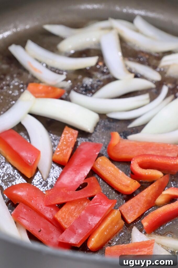 Sliced bell peppers and onions cooking in a skillet