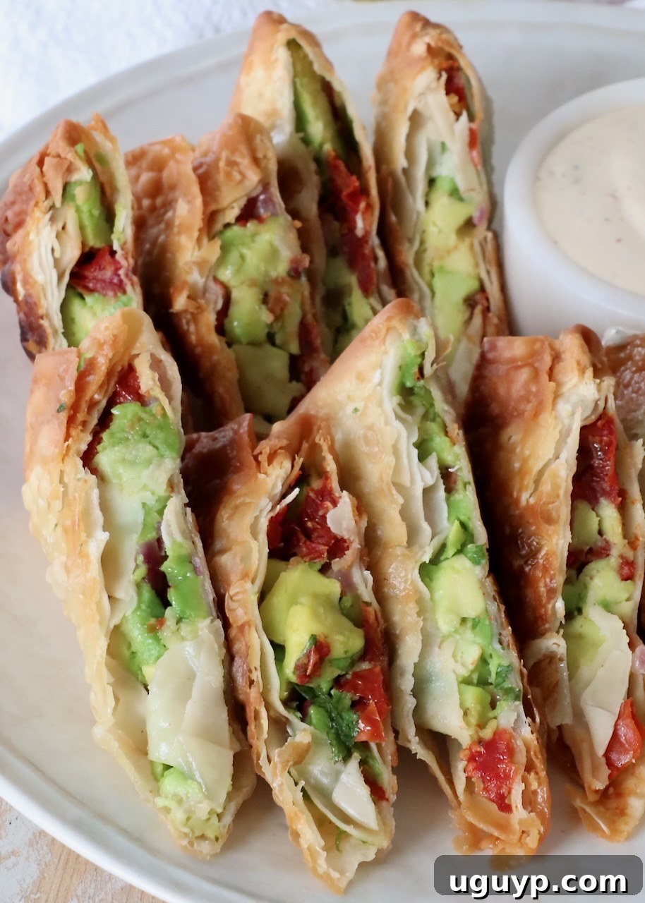 A stunning close-up of crispy avocado egg rolls, sliced diagonally, showcasing their rich green interior, elegantly presented on a white plate with no dipping sauce, highlighting their natural beauty.