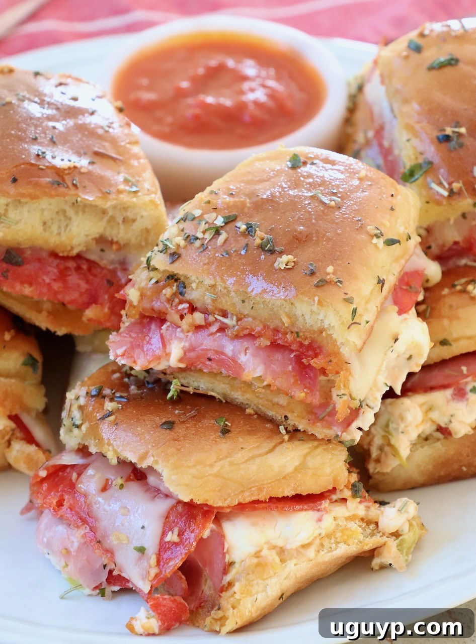 Hot Italian Sliders stacked on a serving plate with a small bowl of marinara sauce on the side
