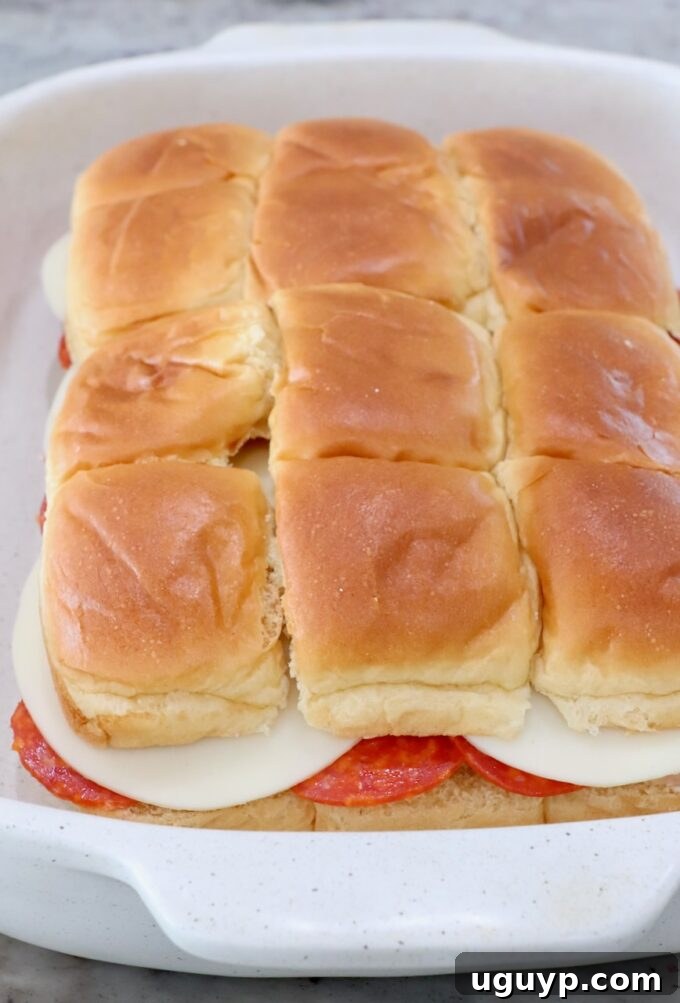 Italian sub sliders in a casserole dish before brushing with butter
