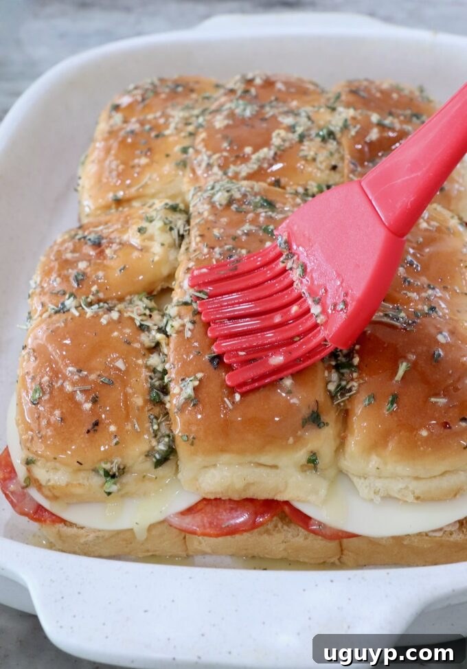 Italian sub sliders in a casserole dish brushed with herb butter