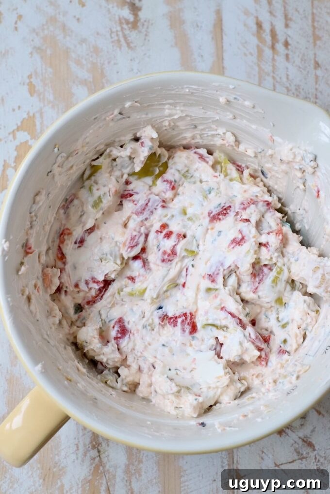 Cream cheese mixed with roasted red peppers, pepperoncinis, and Italian seasoning in a bowl