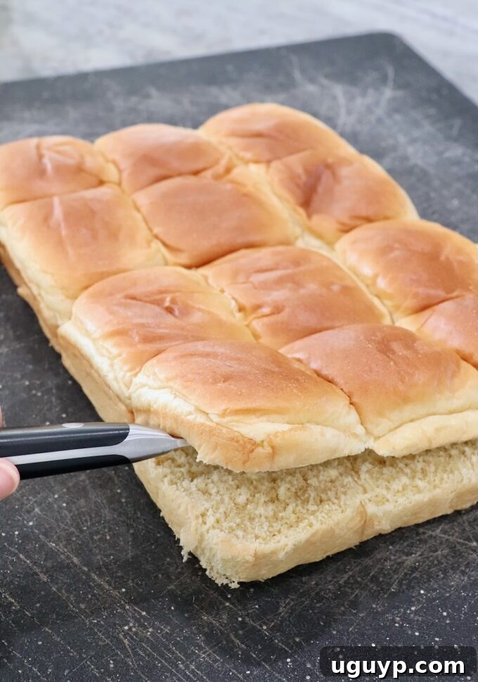 Brioche rolls sliced through the middle with a knife on a cutting board
