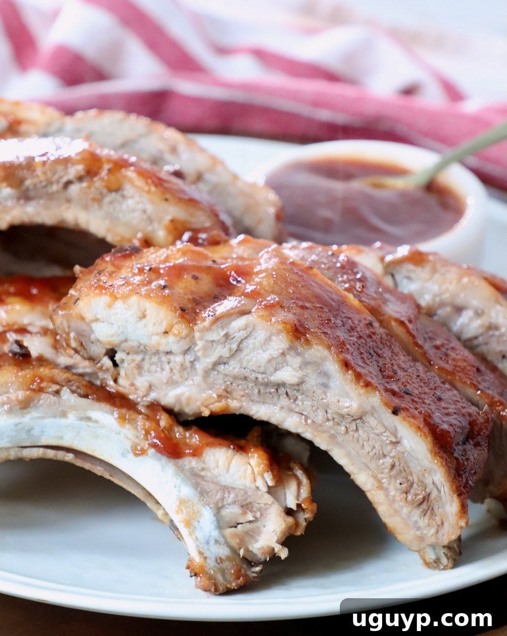 Cooked baby back ribs sliced into individual portions and arranged on a plate.