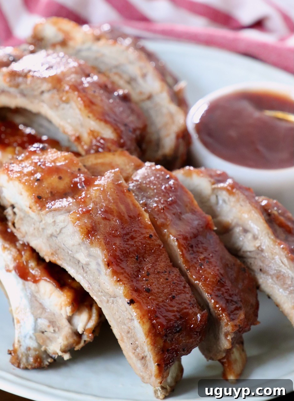 Cooked baby back ribs, brushed with BBQ sauce, presented beautifully on a plate.
