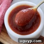 Close-up of Jack Daniel's BBQ sauce in a small bowl with a mini spoon, highlighting its glossy, rich texture and inviting color.