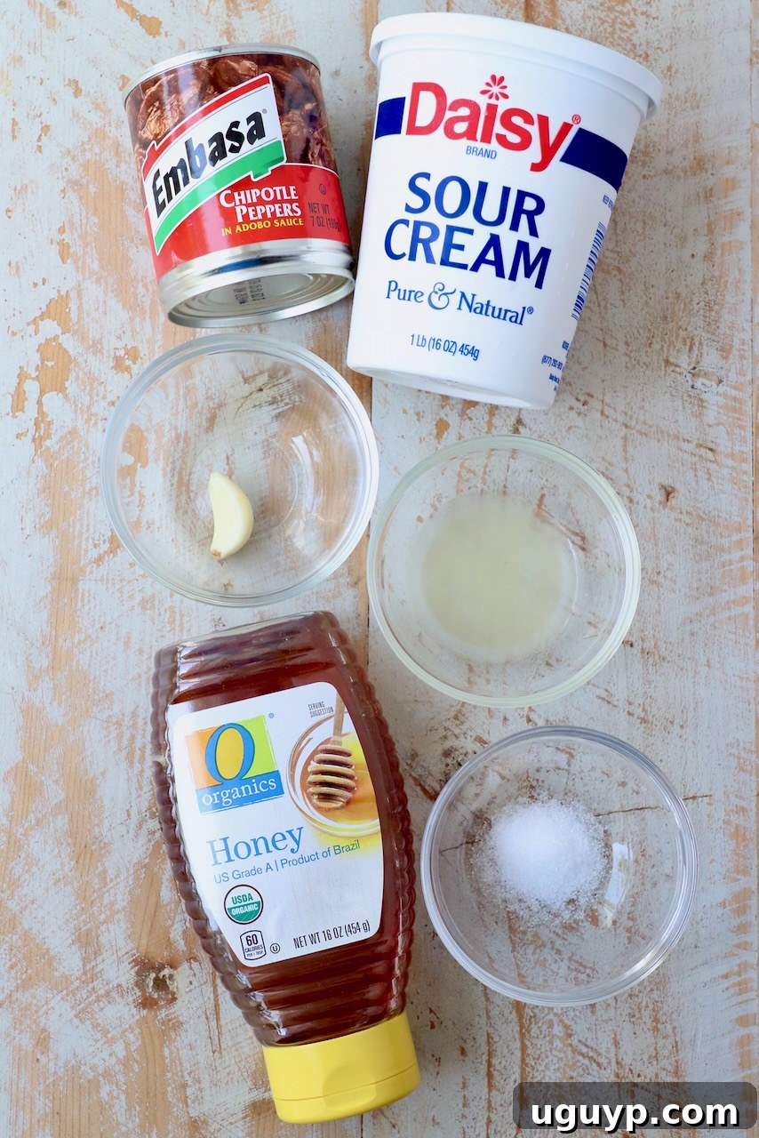 ingredients for creamy chipotle sauce laid out on a white wooden board