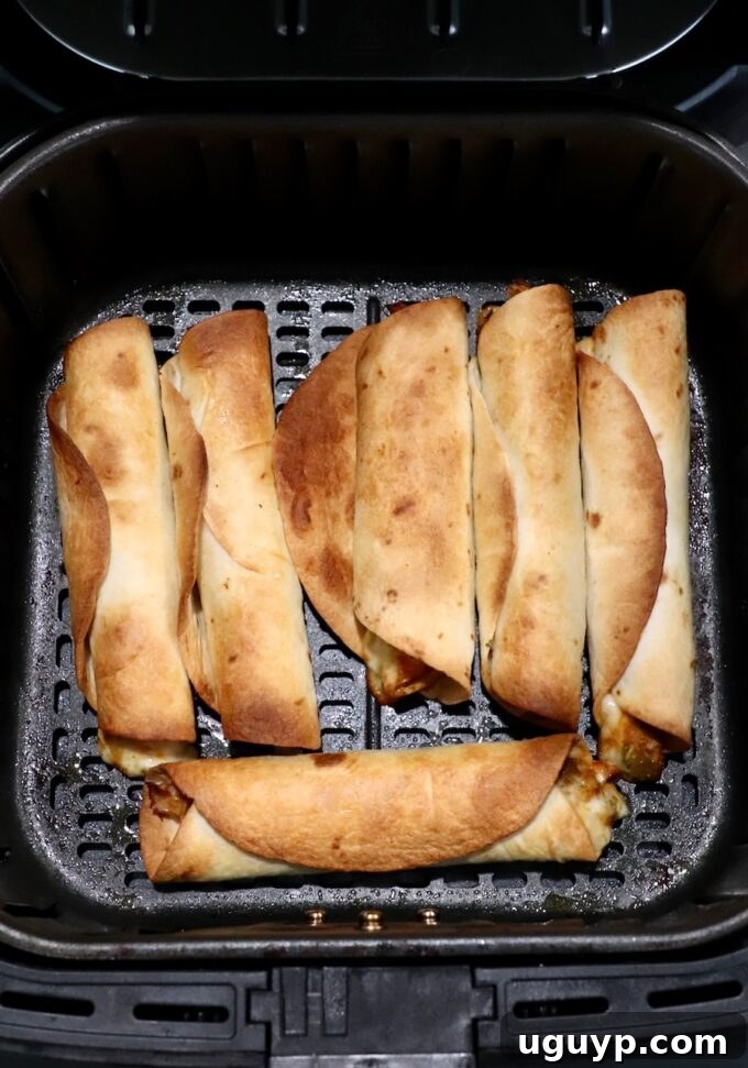 cooked taquitos in an air fryer basket