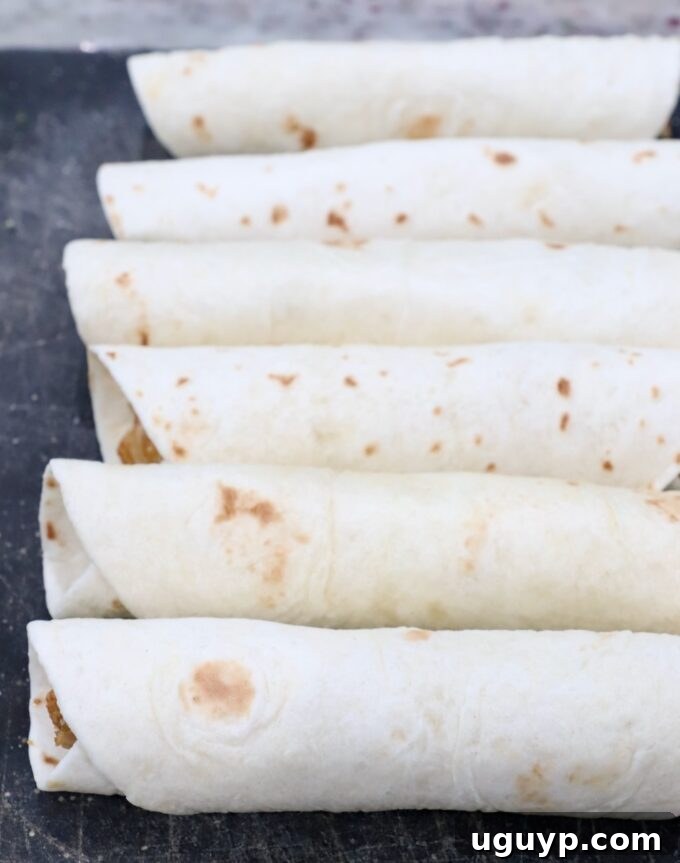 prepared taquitos, uncooked, on cutting board