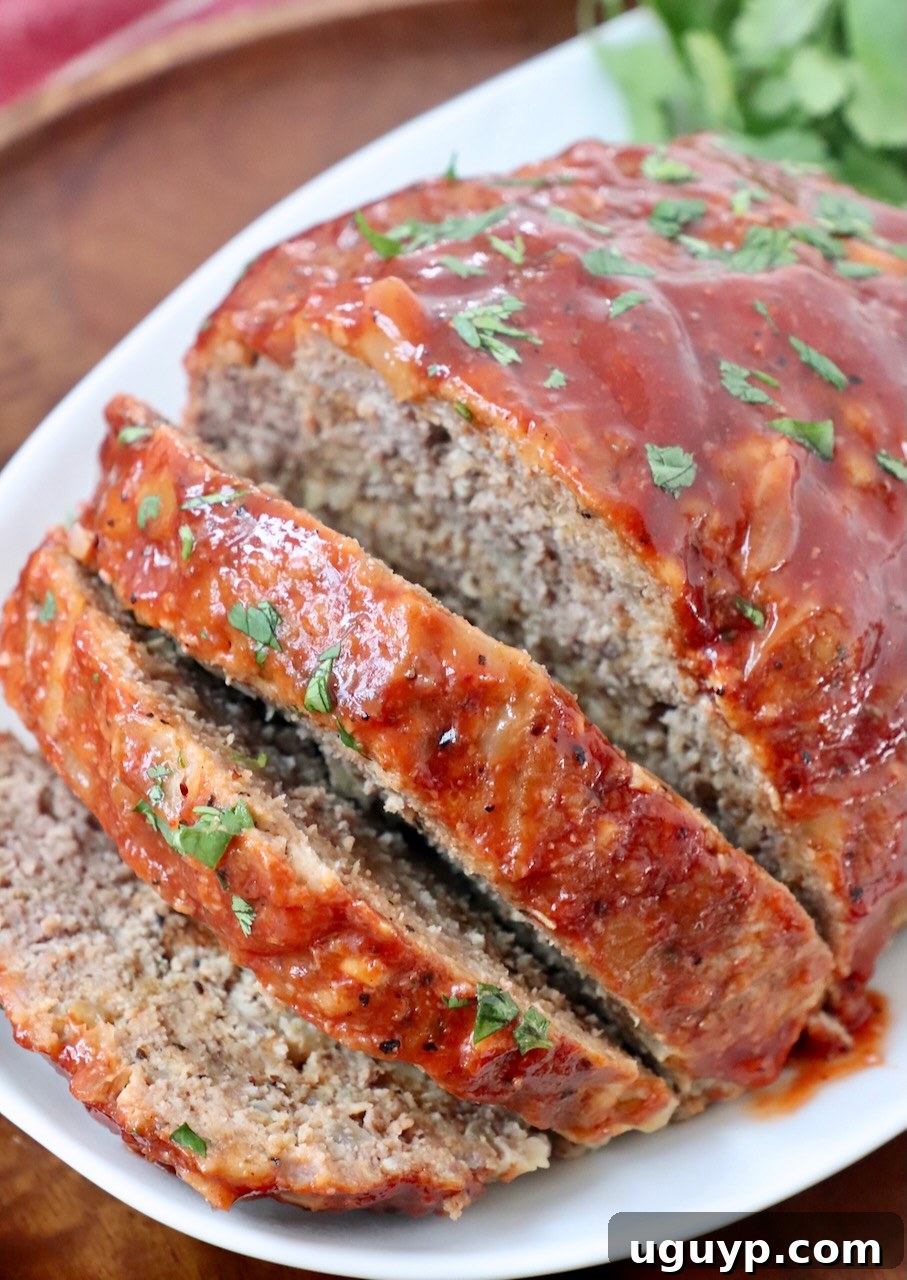 Perfectly sliced Crock Pot Meatloaf on a plate, garnished with fresh parsley, ready to serve for a family dinner.