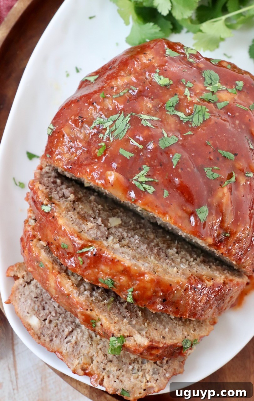 A beautifully presented plate with a generous slice of Crock Pot Meatloaf, showing off its perfectly cooked texture and rich glaze.
