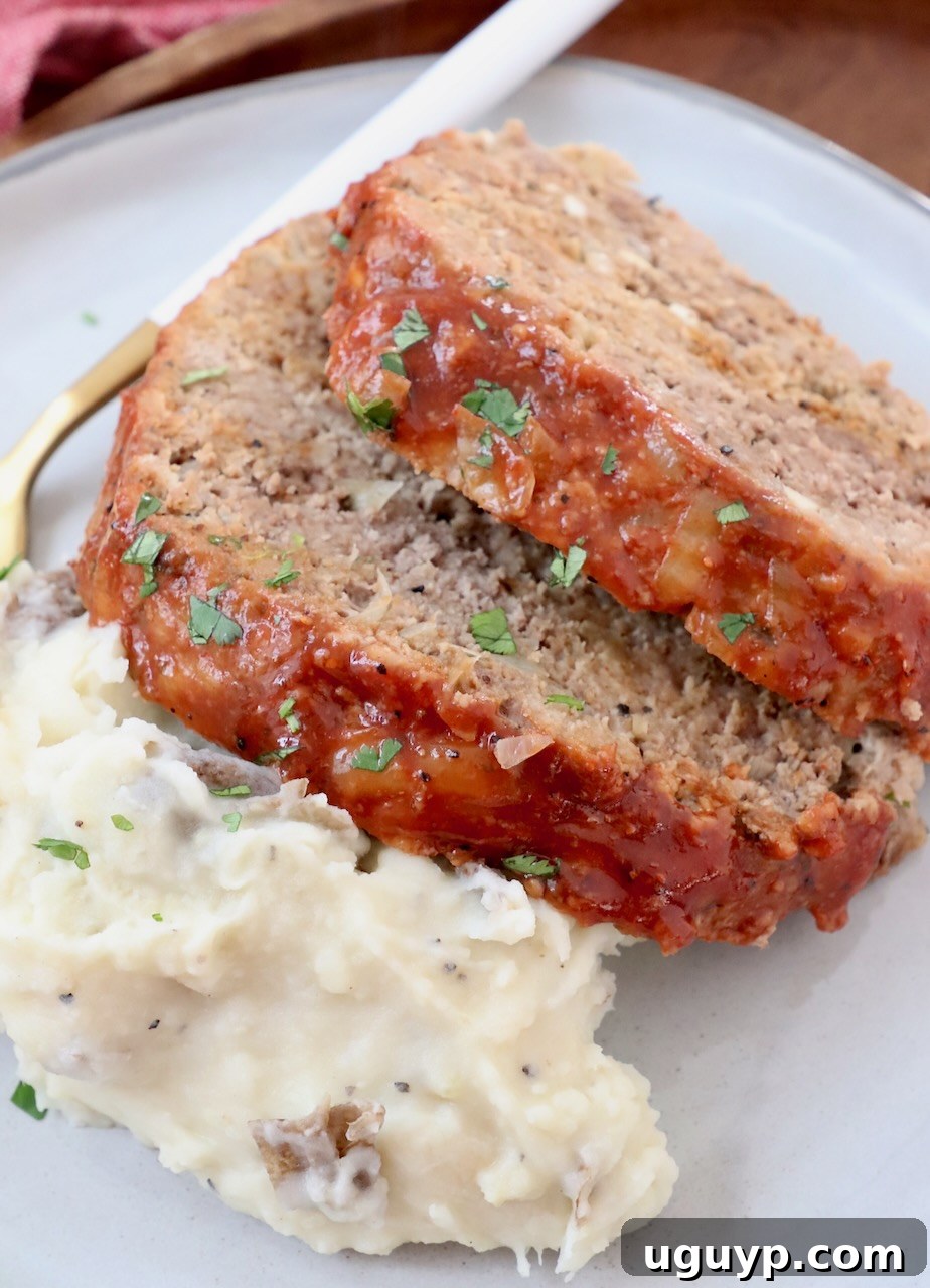Two generous slices of Crock Pot Meatloaf served alongside a mound of creamy mashed potatoes, making for a hearty and satisfying meal.