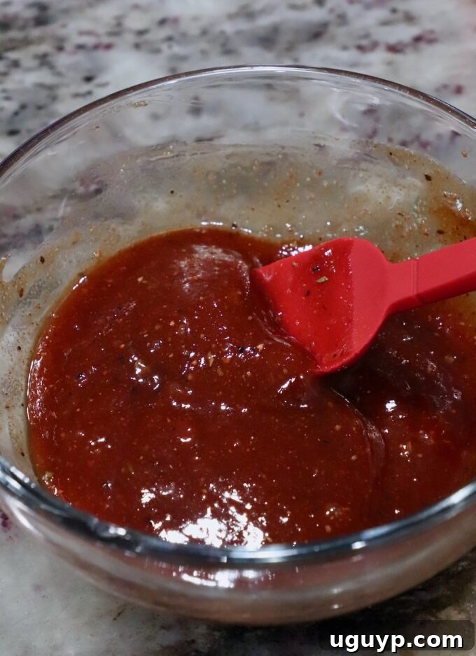 A small bowl of homemade BBQ sauce or meatloaf glaze, accompanied by a pastry brush, ready to coat the meatloaf.