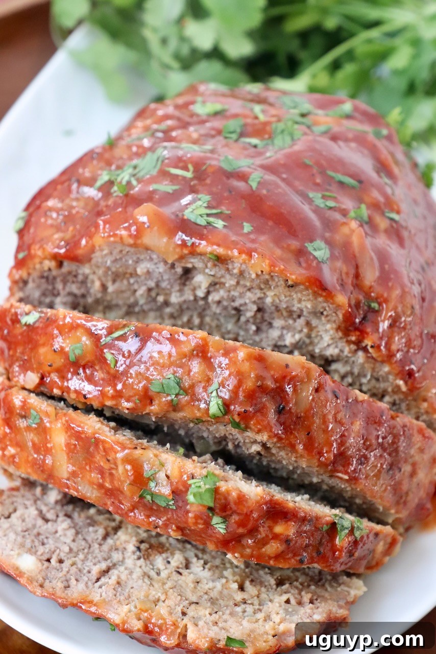 A freshly sliced, tender meatloaf on a plate, showcasing its juicy interior and flavorful glaze, ready to be served as a hearty meal.
