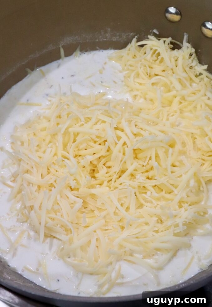 grated cheese in creamy sauce in saucepan