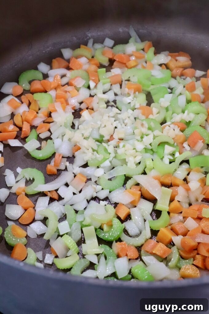 Diced onions, carrots, celery, and minced garlic sautéing in a large pot with olive oil.