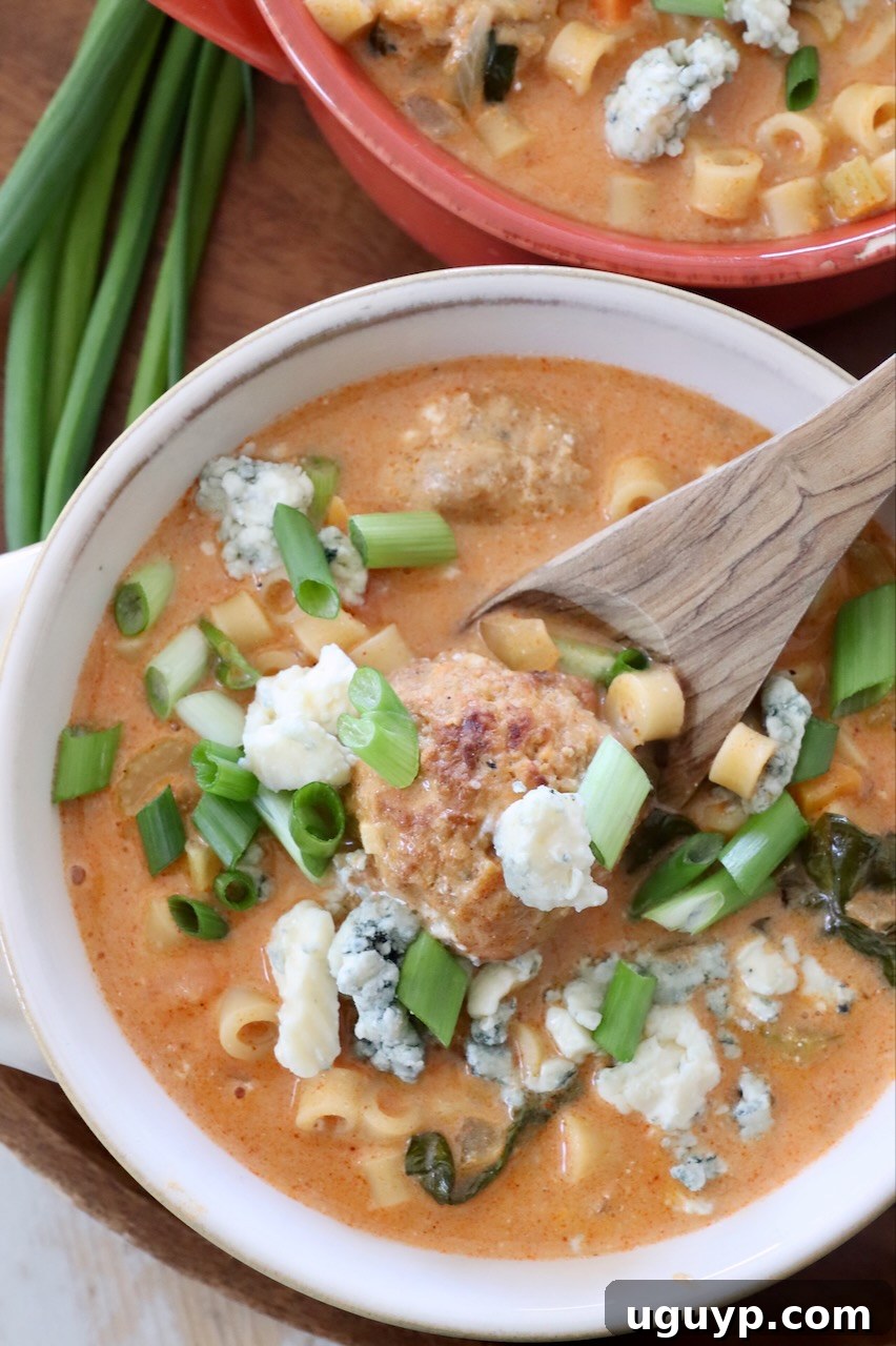 Warm bowls of Buffalo Chicken Meatball Soup served with a spoon.