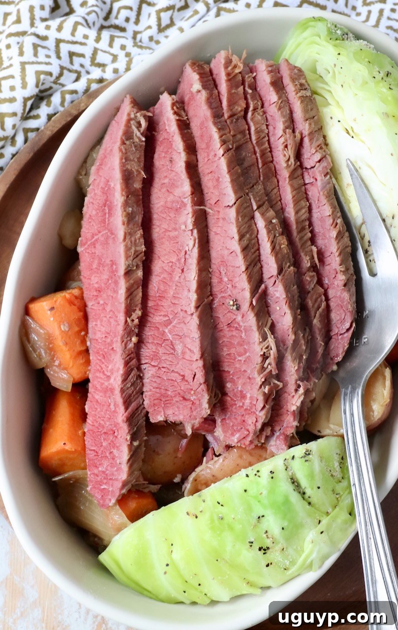 A serving dish with expertly sliced corned beef, accompanied by a generous portion of perfectly steamed cabbage, showcasing a classic pairing.