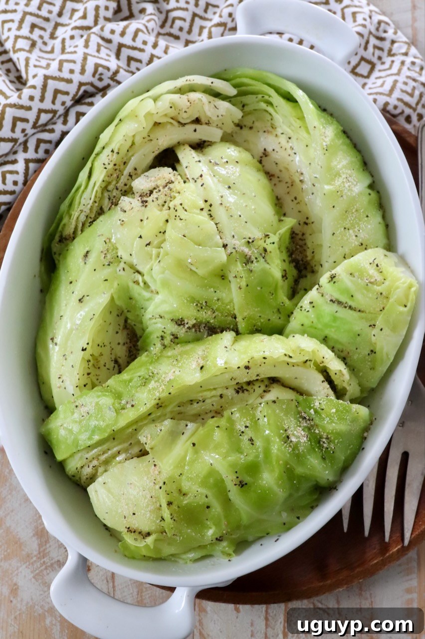 Close-up of steamed cabbage wedges in a white serving dish, garnished and ready for a meal.