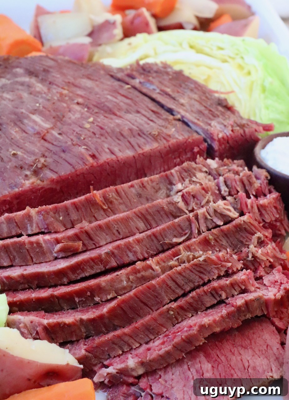 sliced corned beef on platter with cooked carrots, potatoes and cabbage