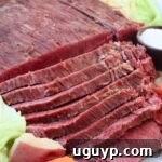 sliced corned beef on plate with cabbage, potatoes and carrots
